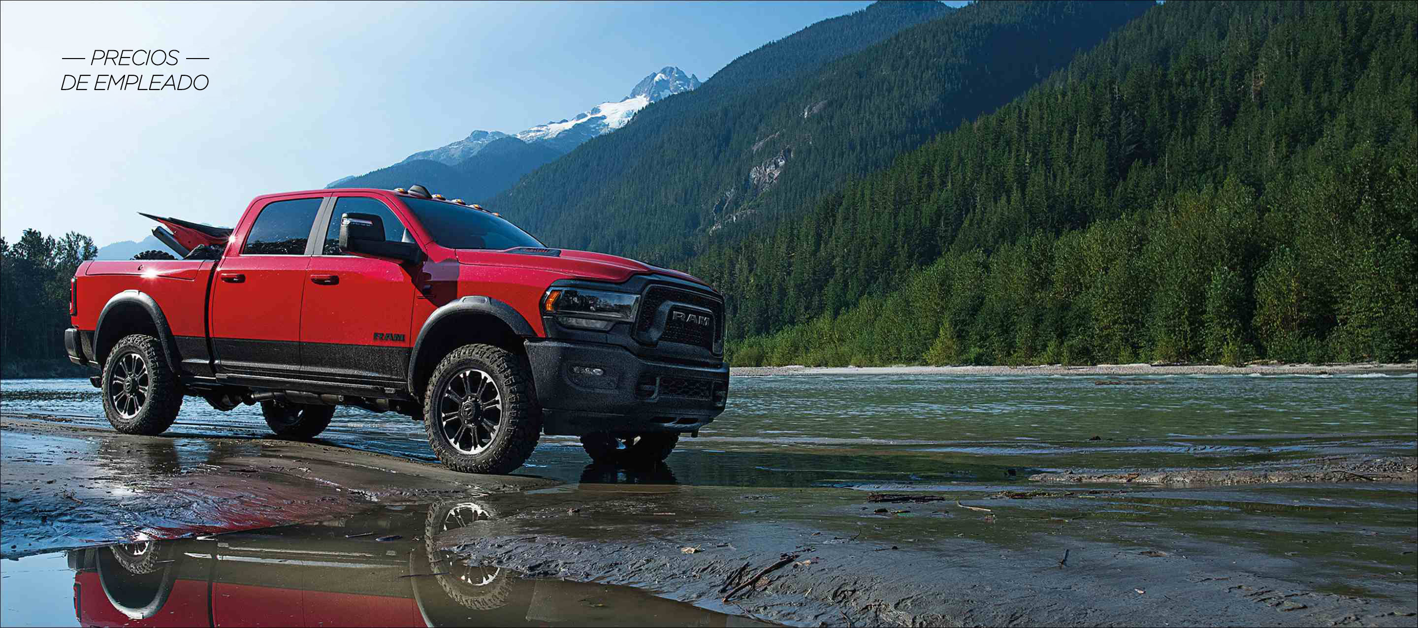 Una Ram 2500 Rebel 4x4 Crew Cab 2024 roja con un ATV en su plataforma, con montañas de fondo. Evento de ventas Precios de empleado.